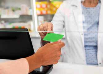Pharmacist giving loyalty card to customer in the pharmacy store.
