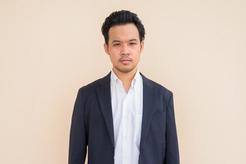 Portrait of Asian businessman wearing suit against plain background