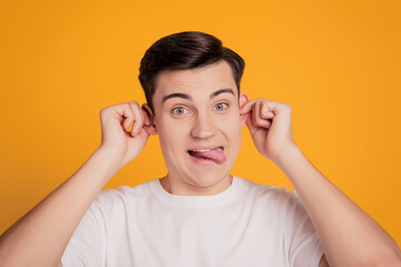 Portrait of funny childish crazy guy have fun grimacing mocking on yellow background