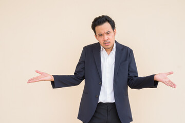 Portrait of Asian businessman wearing suit against plain background and looking angry and confused