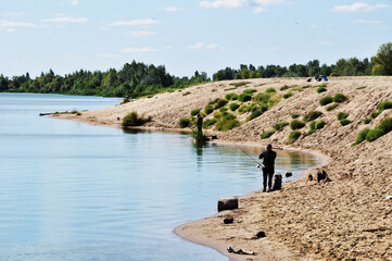 Panorama of the lake. Fishermen on the shore of the lake are fishing. Autumn, sunny day.