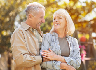 Romantic senior couple enjoying the moment of love in park, walking at sunny autumn day and...