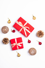 Christmas composition. Red gift box, pine cones, gold and red ornament decorations on white background. Winter holidays concept. Top view