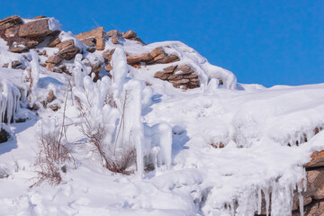 Winter Baikal. Dry grass on the rocky slope is covered with ice and snow. Natural background - 461062271