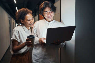 Workers looking at screen of laptop with happiness