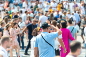 Crowd of people and man with phone on busy city street