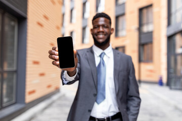 African american businessman showing smartphone with empty screen, recommending new mobile application or website