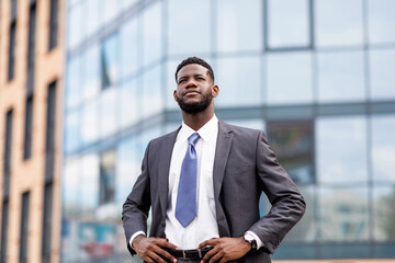 Young african american businessman posing by office center, happy male entrepreneur having break and walking outdoors