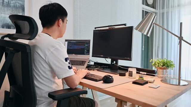 Freelance asian man working and coding with computer on wooden desk in modern office