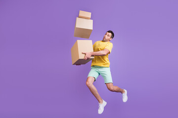 Full length body size photo man jumping with heavy carton boxes isolated pastel violet color...
