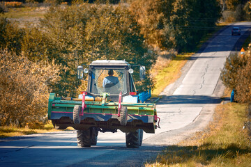 Tractor with plow driving on hilly road at countryside, agricultural autumn work. Tractor with...