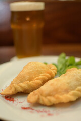plate menu with Argentine empanadas with beer on a table in a night bar