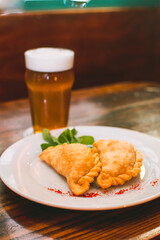 plate menu with Argentine empanadas with beer on a table in a night bar