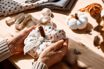 Cozy pumpkins. Woman making colorful fabric pumpkins. Autumn decoration with handmade textile...