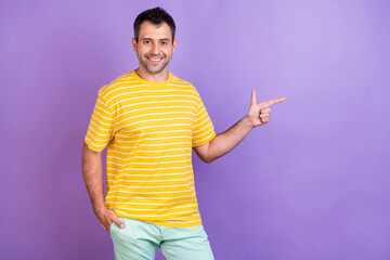 Fototapeta premium Photo portrait man in t-shirt pointing copyspace smiling isolated pastel purple color background