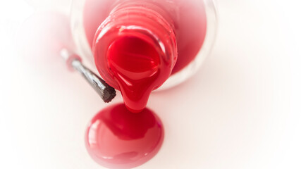 pouring red nail polish from bottle on white background