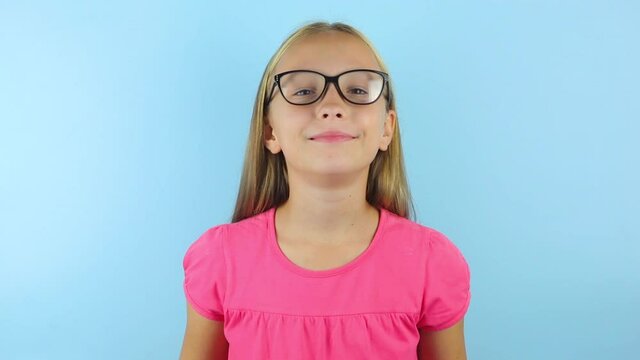 girl in a good mood on a blue background puts on glasses for correcting vision.