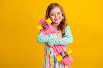 Photo of young girl happy positive smile hug cuddle skateboard sporty isolated over yellow color...