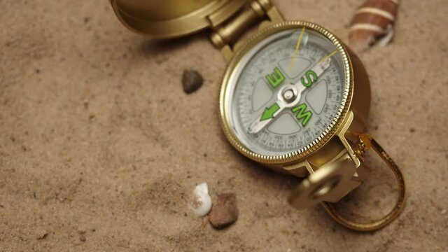 Gold compass on sand background close-up, focusing of golden compass. Traveling and tourism concept, navigation.