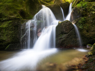 Fototapeta na wymiar Long exposure waterfall over brown and green rocks at Bad Kreuzen Austria