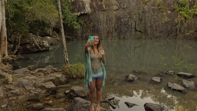 Gorgeous Woman Taking A Picture At The Majestic Cedar Creek Falls  In Proserpine,  QLD, Australia. wide shot