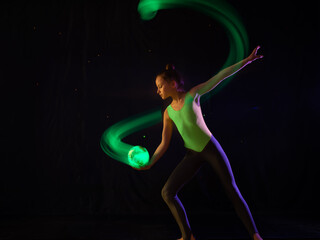 Girl gymnast doing exercise with shining ball in shape of earth with light painting effect
