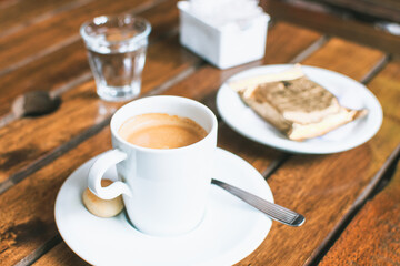 cup of coffee with a glass of water and a plate with alfajor in the restaurant in the afternoon outdoors