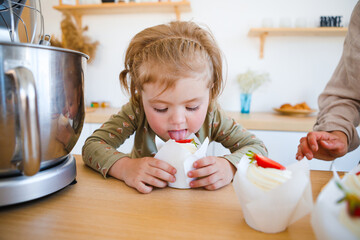 Mom and daughter are baking a beautiful dessert with cream.