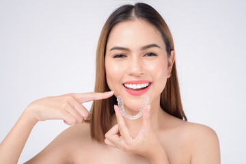 Young smiling woman holding invisalign braces in studio, dental healthcare and Orthodontic concept - obrazy, fototapety, plakaty