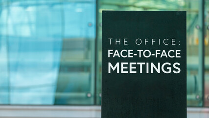 The Office: Face to Face Meetings on a city-center sign in front of a modern office building 