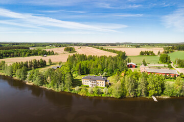 Fototapeta premium Kouvola, Finland - June 3, 2021: Aerial view of beautiful wooden Rabbelugn Manor - Takamaan Kartano. River Kymijoki bank.