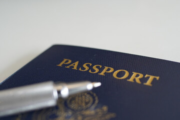 a blue passport with a pen on a desk