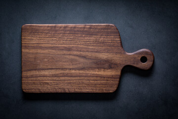 Black walnut handmade wooden chopping board. Handmade black walnut wooden cutting board on dark tone texture background.