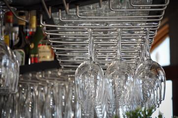 Wine glasses hanging upside down on the bar rack