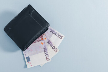 Black wallet and 500 euro bills on gray.