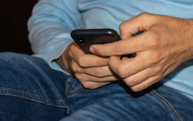 Young male hands holding a mobile phone and typing a message