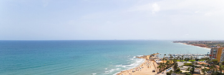 Cropped image panoramic view Mediterranean Sea and coastline with sandy beach of Dehesa de Campoamor, clear blue sky copyspace for text. Travel, summer holidays concept. Spain, Costa Blanca, Alicante
