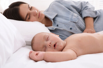 Mother with her cute baby sleeping in bed