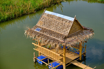 The thatched roof bamboo huts floating on the pond for a relaxing vacation. There is a solar cell on the roof.