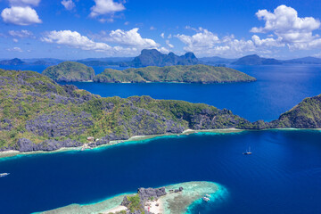 Beautiful coral reef, boats and a clear ocean on Matinloc Island, Bacuit Archipelago, El Nido, Palawan, Philippines. Aerial drone view.