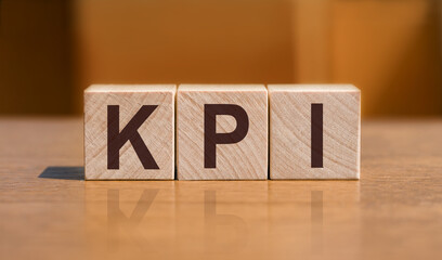 KPI - key performance indicator, text on wooden cubes on orange wall background.