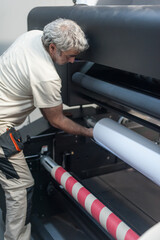 Technician operator changes paper roll on large printer plotter machine