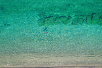 Young woman in a swimsuit swimming in sea water on the beach. View from above. Top, drone view