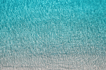 Fototapeta na wymiar Blue, turquoise transparent water surface of ocean, sea, lagoon. Horizontal background. Top view of sand beach. Aerial, drone view