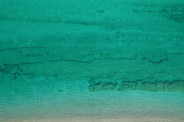 Relaxing aerial beach view with calm sea water and stone, slabs, lump, coral. Summer vacation. Blue ocean lagoon, sea shore, coastline. Drone, copter top view.