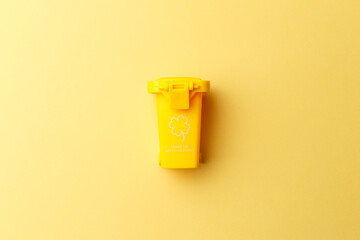 Yellow dumpster on yellow background close-up. Container for disposal garbage waste and save environment. Dustbin for recycle. The concept of ecology. Separate garbage collection