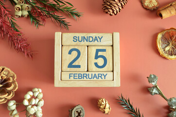 February 25, Cover design with calendar cube, pine cones and dried fruit in the natural concept.