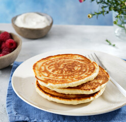 Pancakes for breakfast with sour cream, raspberry jam and fresh raspberries.