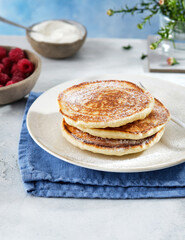 Pancakes for breakfast with sour cream, raspberry jam and fresh raspberries.