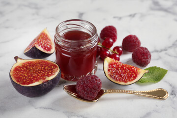 Jar of sweet jam and ingredients on white marble table